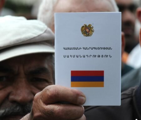 Мужчина держит Конституцию Армении с флагом на обложке