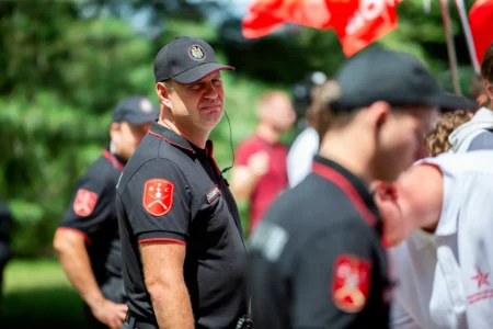 Мужчина в черной форме с нашивкой охранной службы на фоне других участников мероприятия в Молдове