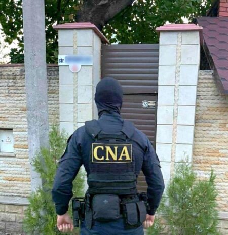 Сотрудник CNA Молдовы у ворот частного дома во время обыска