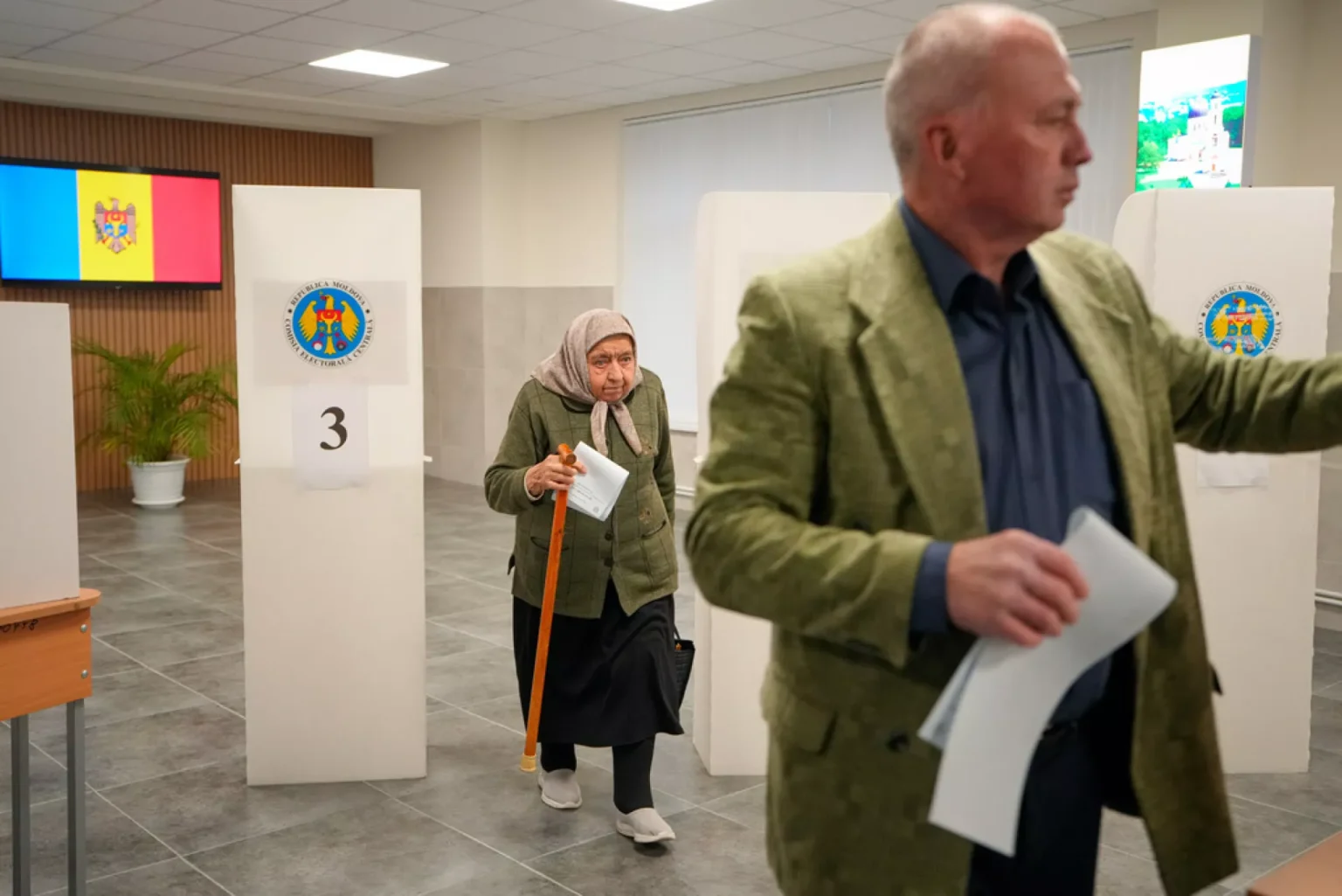 Пожилая женщина выходит из кабинки для голосования на парламентских выборах в Молдове