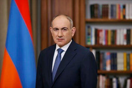 Никол Пашинян на фоне армянского флага и книжного шкафа