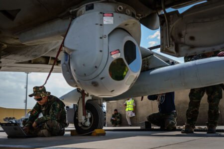 Турецкий военный техник на земле проводит настройку системы воздушного наблюдения под крылом беспилотника