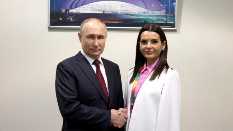 Владимир Путин и Евгения Гуцул пожимают руки на фоне фотографии спортивного комплекса