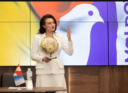 Виктория Фуртунэ выступает с глобусом на фоне флага партии "Moldova Mare"