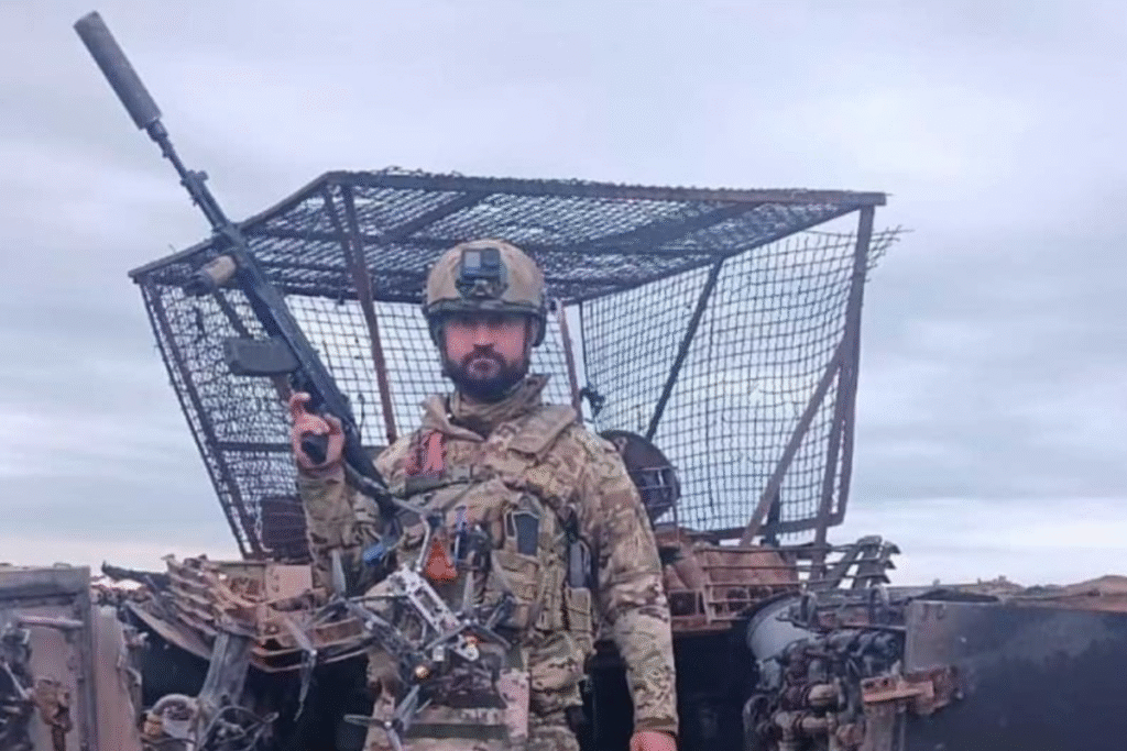 Сербский доброволец в военной форме на фоне уничтоженной техники, с дронами и автоматом