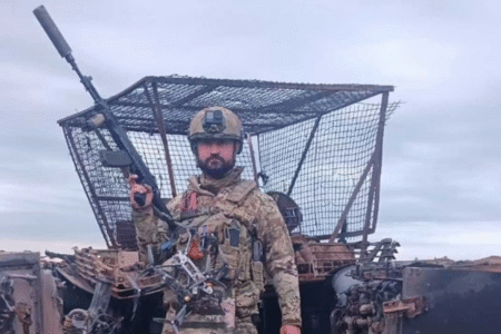 Сербский доброволец в военной форме на фоне уничтоженной техники, с дронами и автоматом