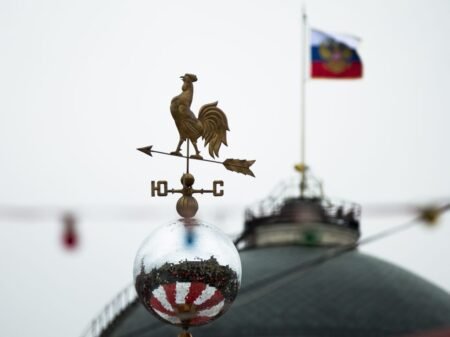 Флюгер на фоне флага России на куполе здания в Москве