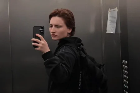 Молодая женщина делает селфи в зеркале лифта