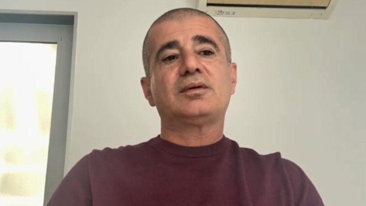 Армянский представитель делегации на фоне белой стены в интервью по видеосвязи