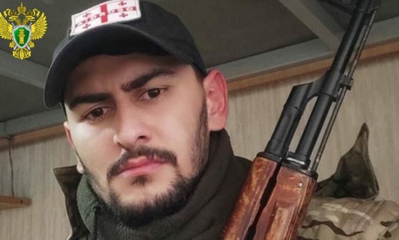 Грузинский боец с автоматом в камуфляже и кепке с флагом Грузии