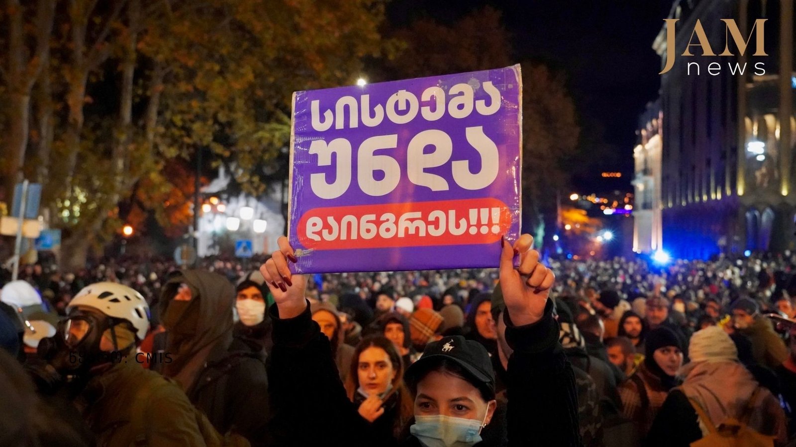Массовый протест в Тбилиси, участница держит плакат на грузинском языке