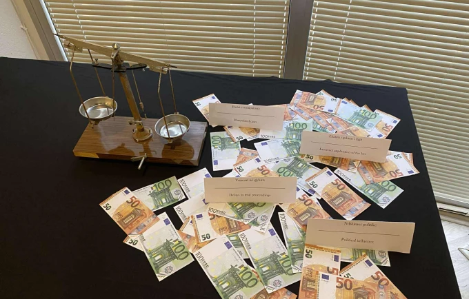 Инсталляция с весами правосудия и банкнотами евро на концептуальной выставке о коррупции в Приштине