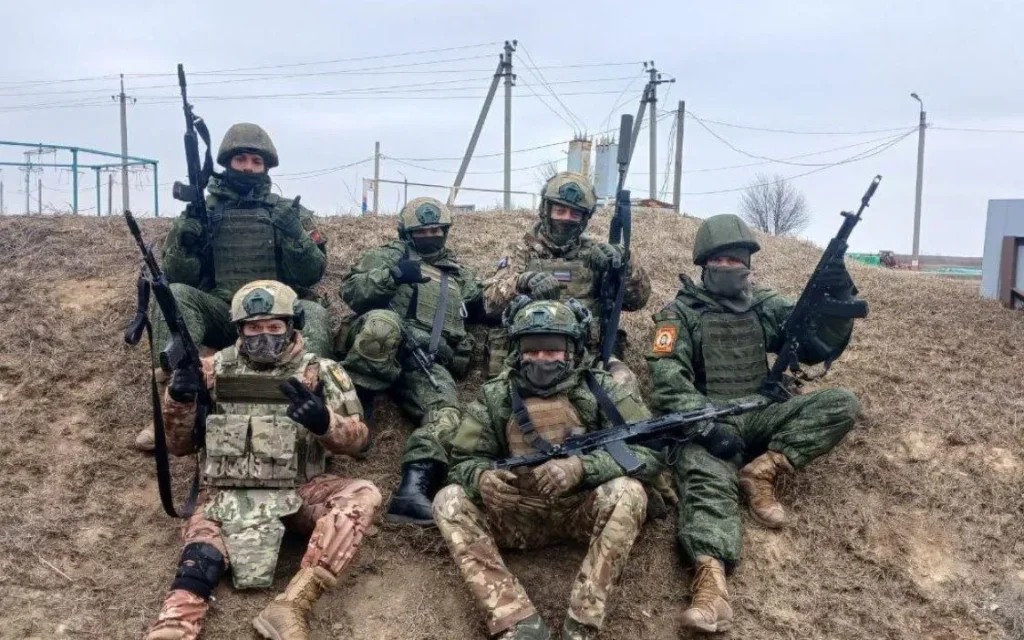 Группа бойцов в камуфляже и тактическом снаряжении позирует с автоматическим оружием на фоне сельской местности