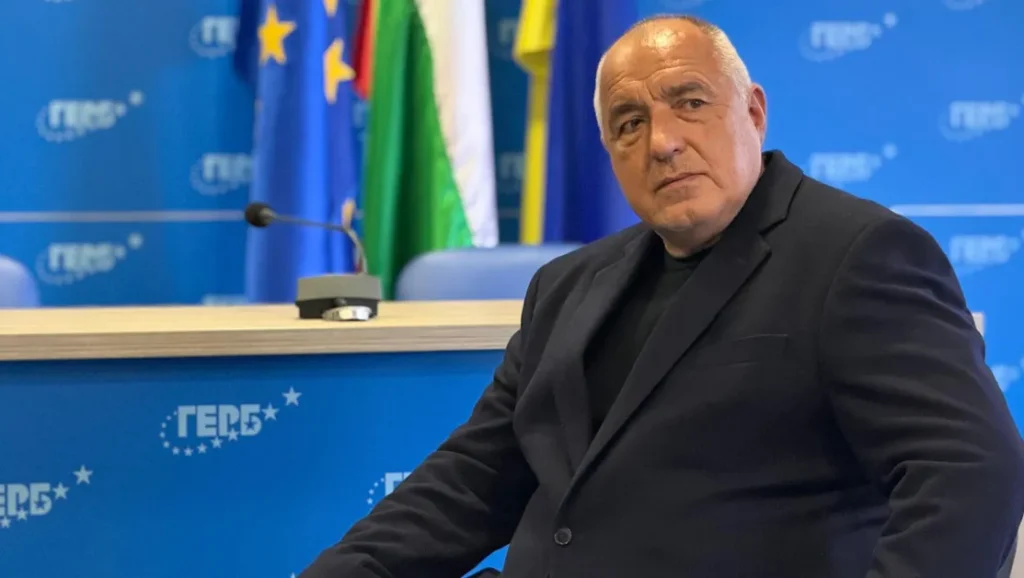 Бойко Борисов сидит за столом на пресс-конференции ГЕРБ на фоне флагов Болгарии и ЕС