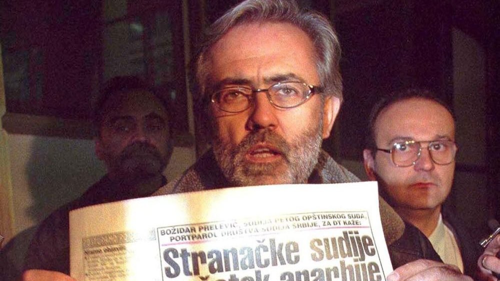 Журналист Славко Чурувия держит газету Дневни телеграф с заголовком «Партийные судьи» на улице Белграда, 1999 год