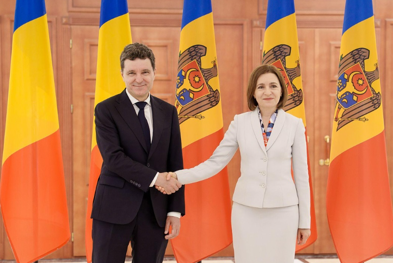 Президент Румынии Никушор Дан и президент Молдовы Майя Санду пожимают руки на фоне государственных флагов обеих стран