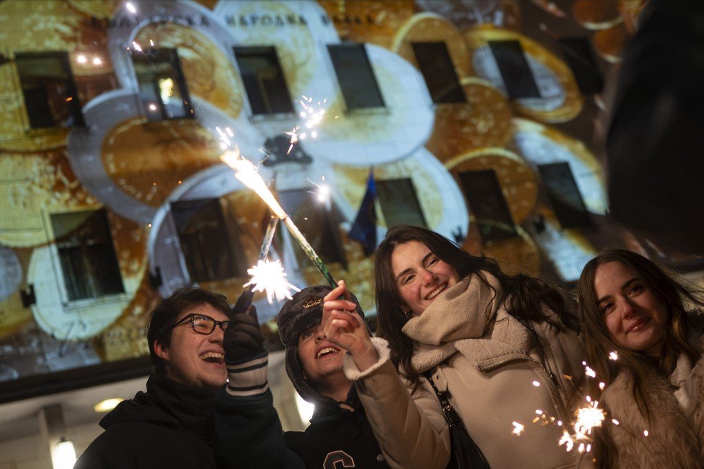 Молодые люди с бенгальскими огнями празднуют переход на евро у здания Болгарского национального банка в Софии