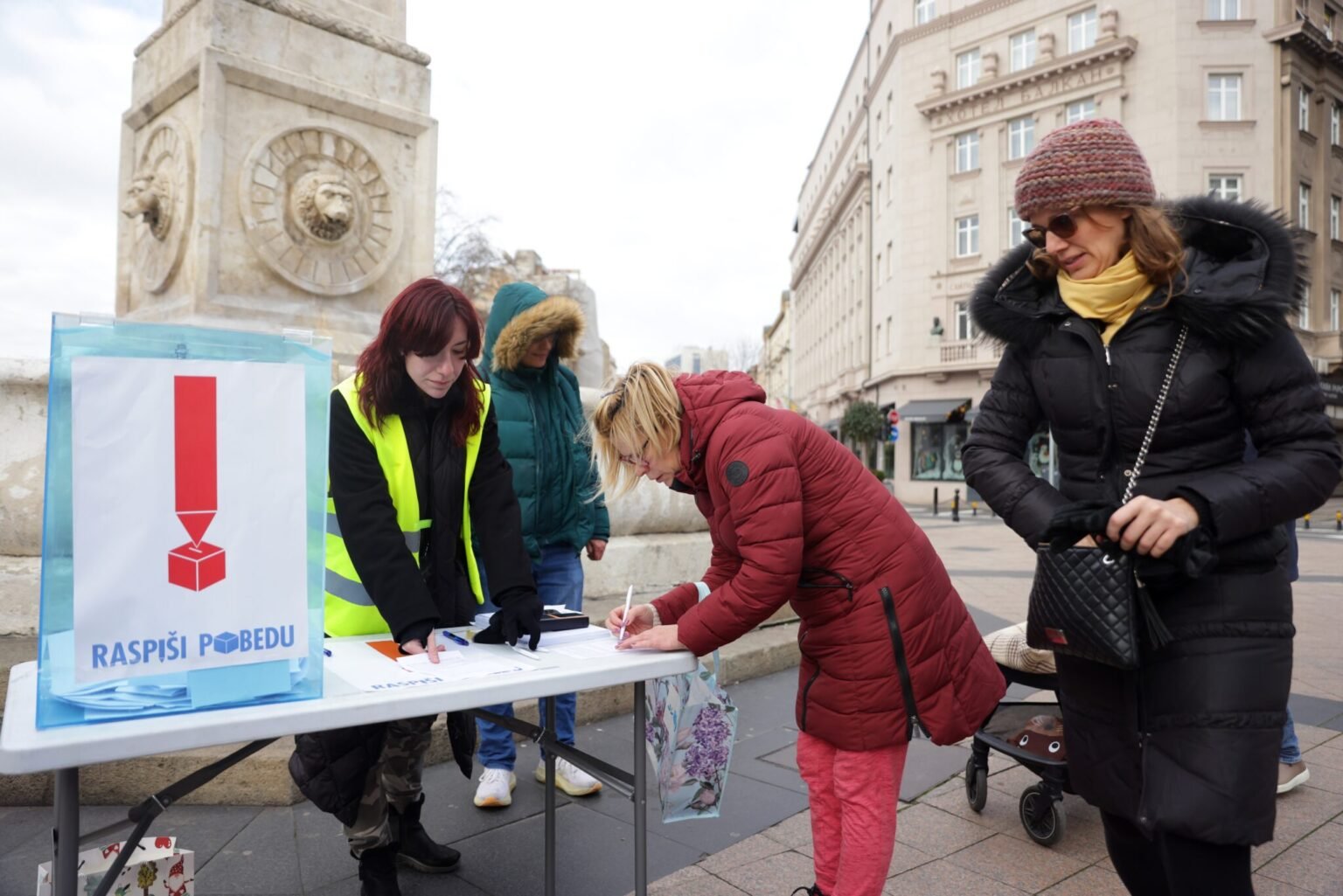 Студенты за столом собирают подписи граждан в поддержку досрочных выборов в Сербии