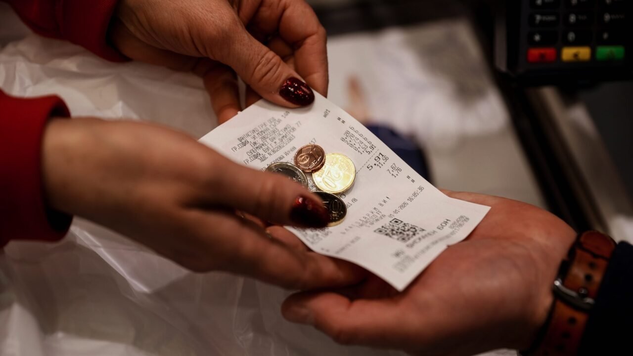 Руки покупателя держат чек и евромонеты — первые расчёты в евро в Болгарии