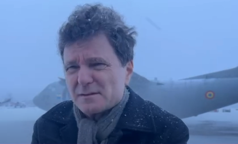 Президент Румынии Никушор Дан стоит на заснеженном лётном поле рядом с военным самолётом Spartan