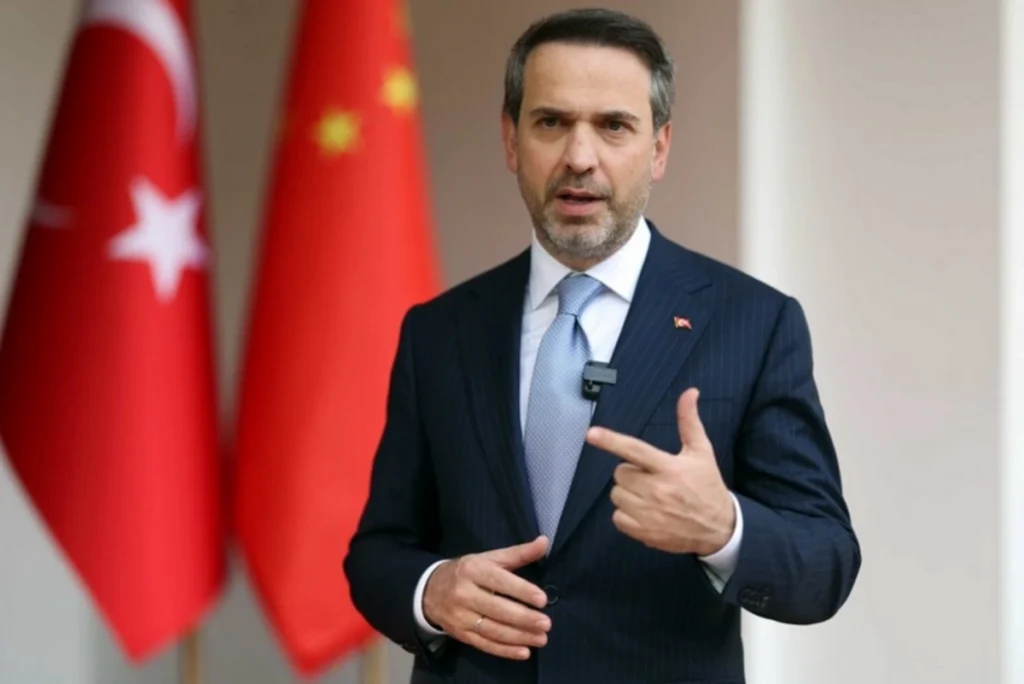 Алпарслан Байрактар, министр энергетики Турции, на фоне турецких флагов