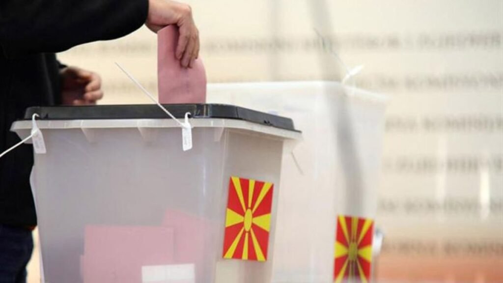 Избиратель опускает бюллетень в урну для голосования с флагом Северной Македонии