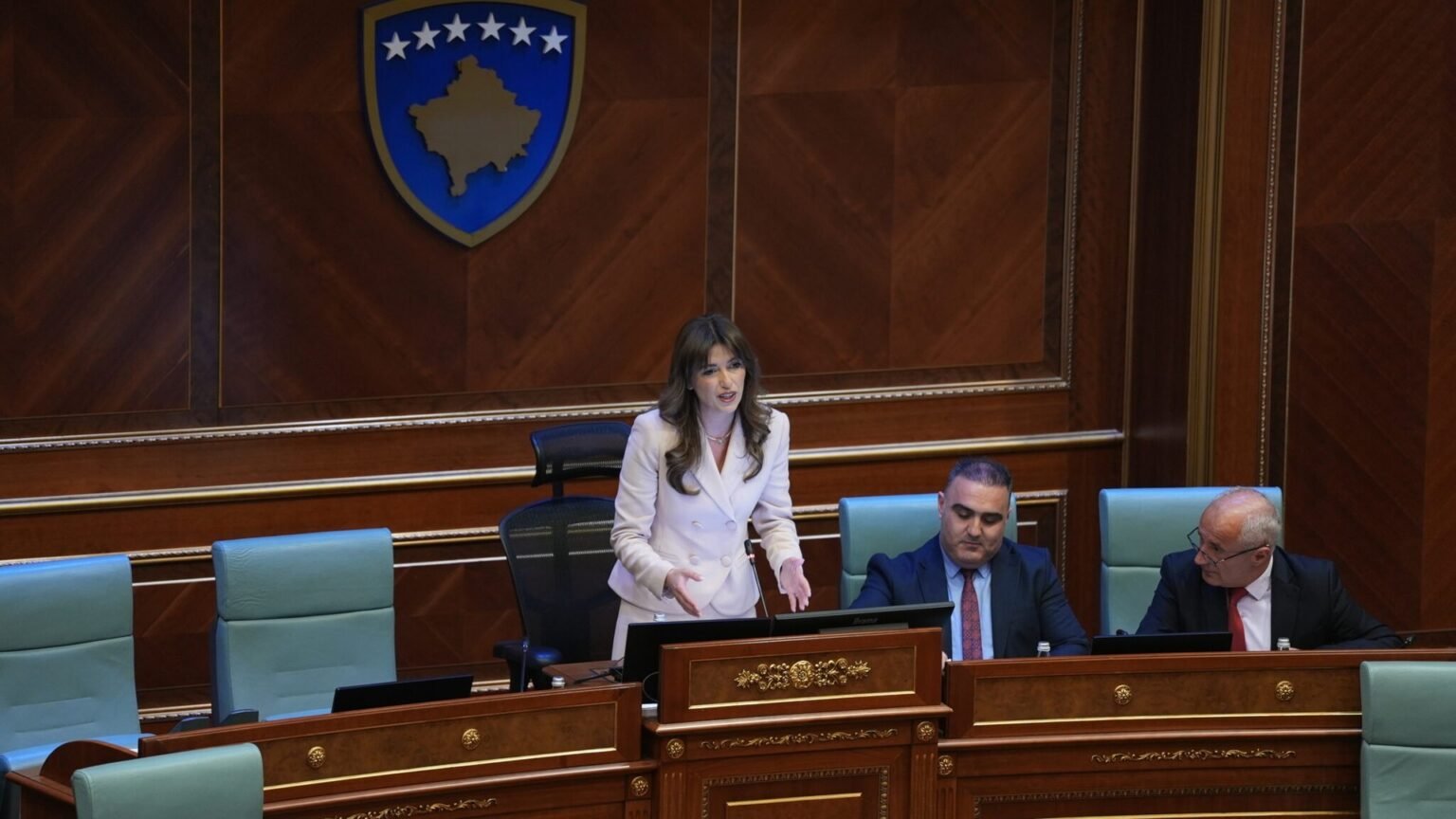 Албулена Хаджиу выступает с трибуны парламента Косово на фоне государственного герба. Албулена Хаджиу, спикер Скупщины Косово. Фото: Balkan Insight