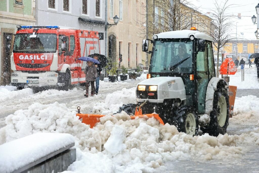 Пожарная машина и снегоуборочный трактор расчищают улицы Марибора во время сильного снегопада