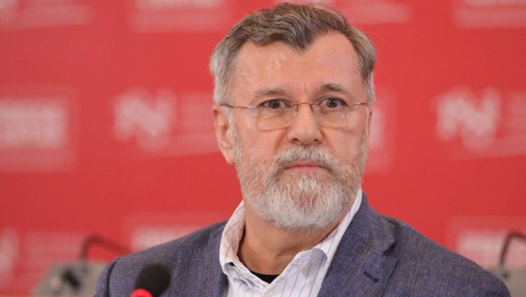 Портрет Верана Матича на красном фоне, выступает на пресс-конференции