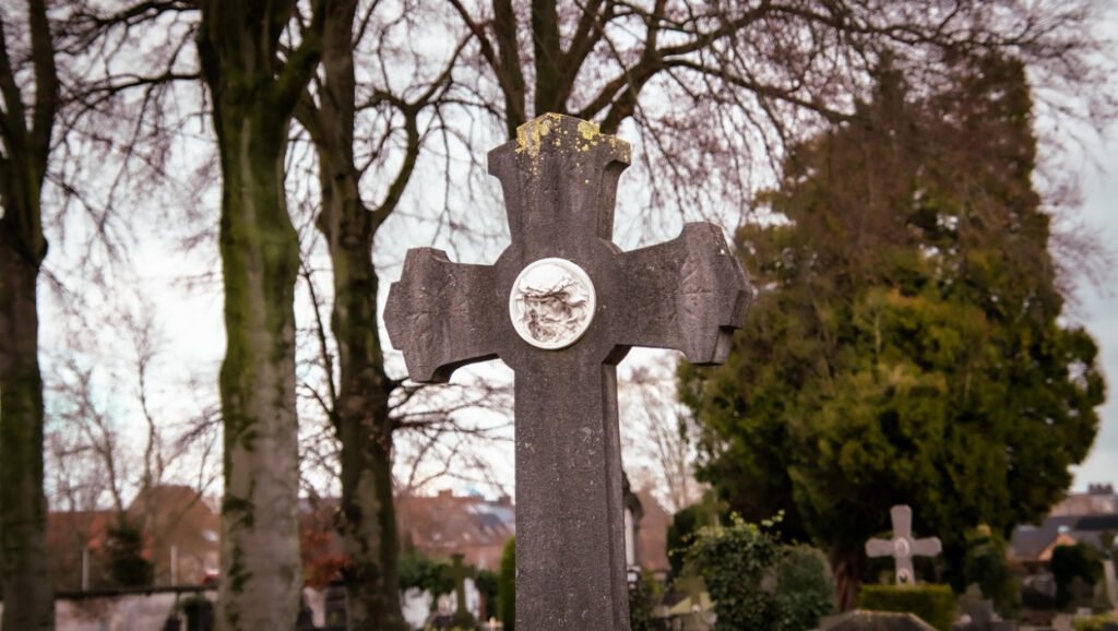 Православный крест с медальоном Христа на кладбище среди голых деревьев