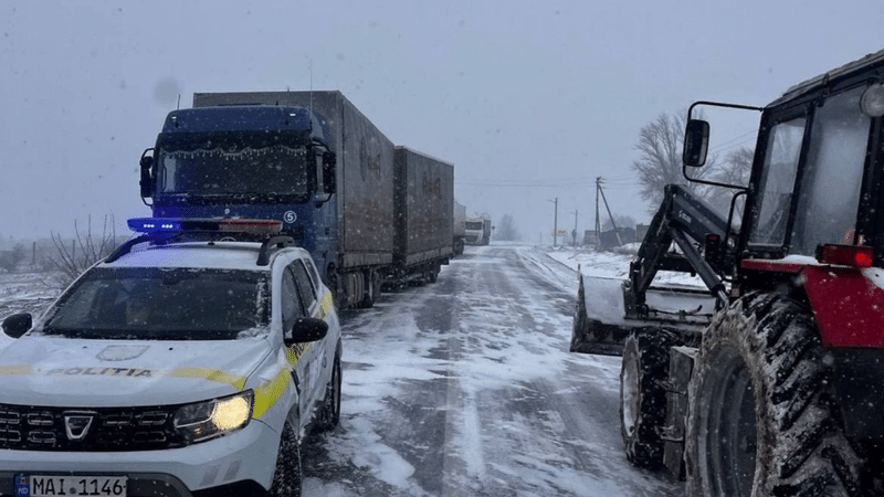 Грузовики и полицейская машина на заснеженной трассе M-3 в Молдове — движение большегрузов приостановлено. Фото: Timpul.md