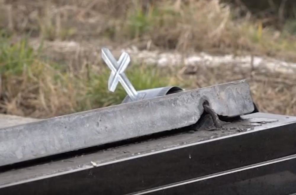 Маленький металлический крест на надгробии со следами снятия или повреждения