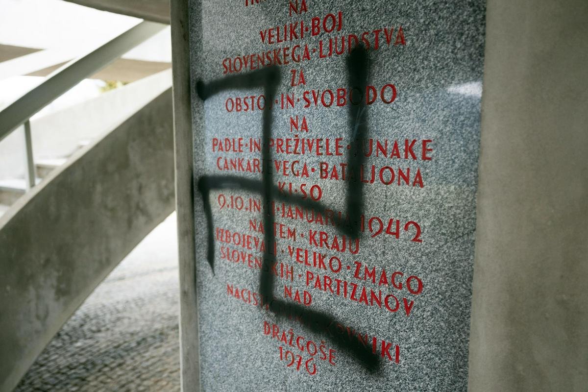 Крупный план мемориальной доски со свастикой и текстом о партизанском сражении 1942 года