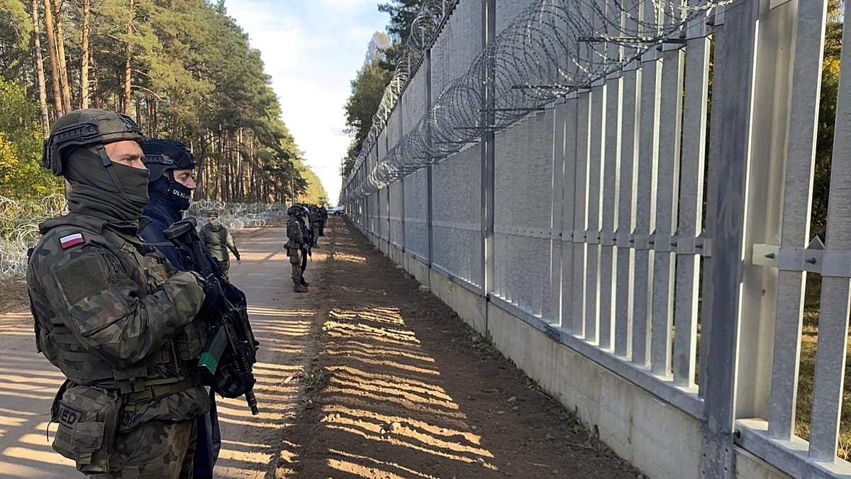 Польские военные патрулируют вдоль пограничной стены с колючей проволокой