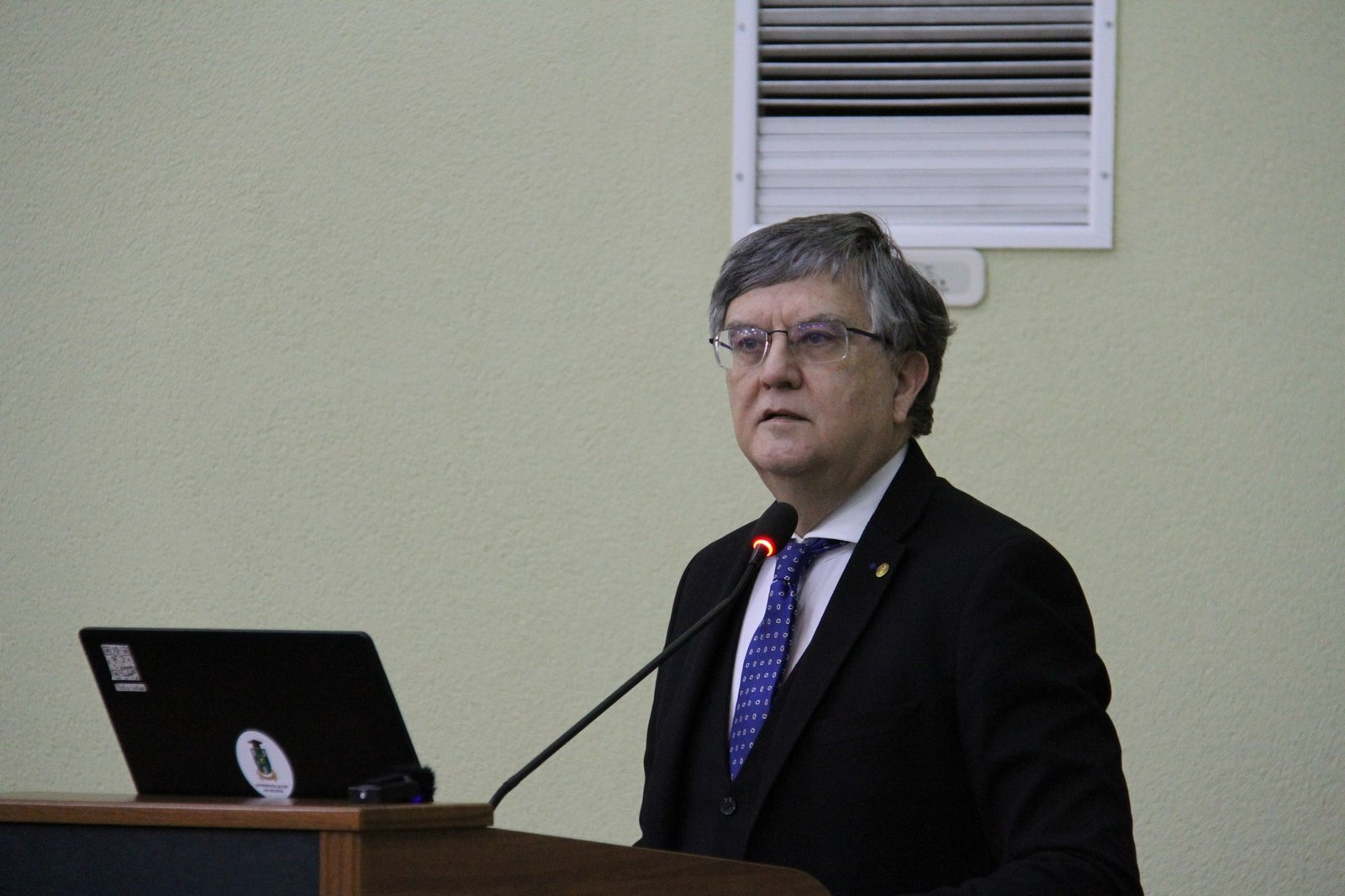 Спикер на трибуне с ноутбуком во время публичной лекции