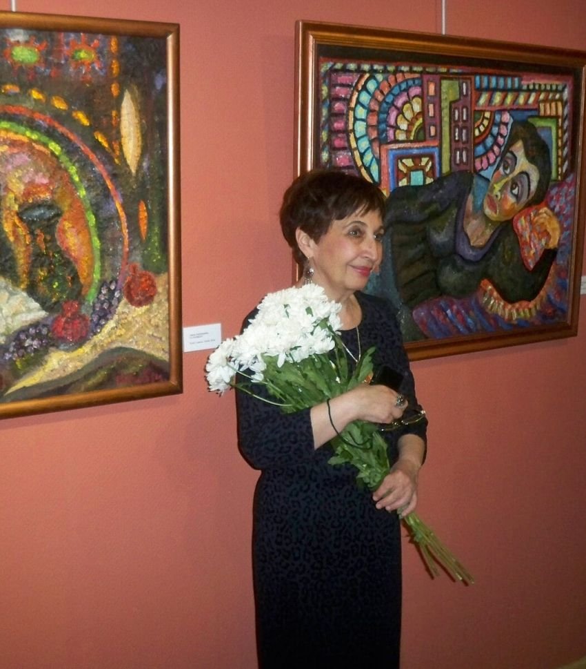 Нина Габриелян на открытии выставки с цветами на фоне своих картин