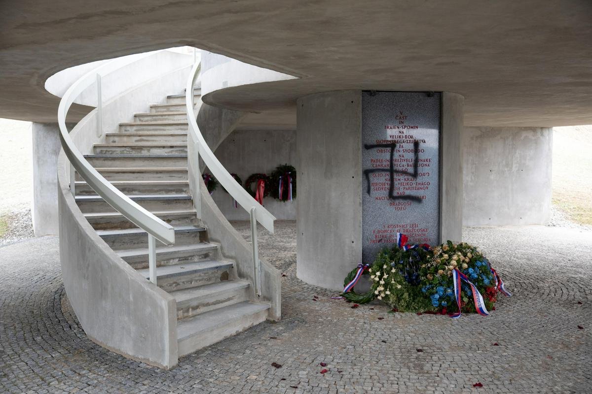 Общий вид интерьера памятника с винтовой лестницей, венками и оскверненной плитой