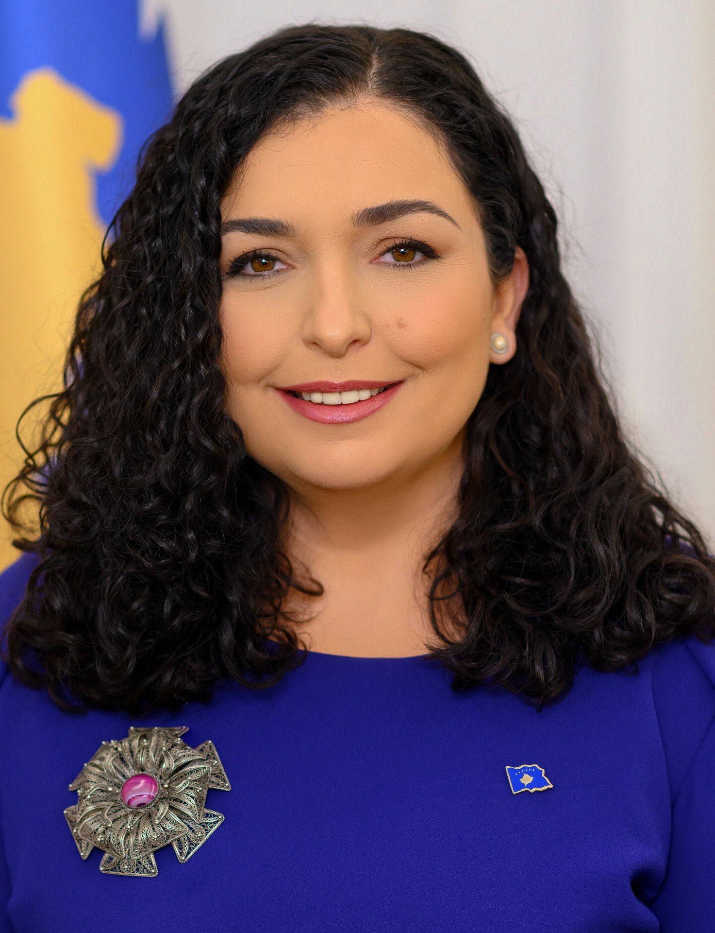 Официальный портрет президента Вьосы Османи на фоне флага Косово