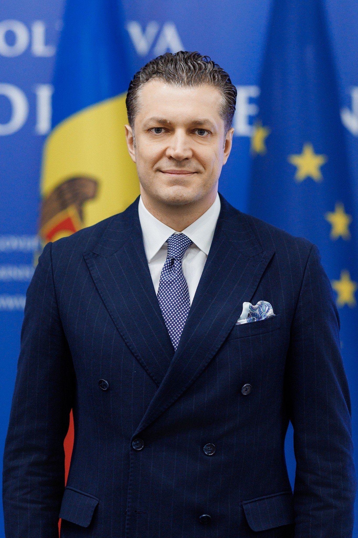 Петру Фрунзе, новый посол Молдовы в Китае, на фоне государственных флагов. Фото: Moldpres