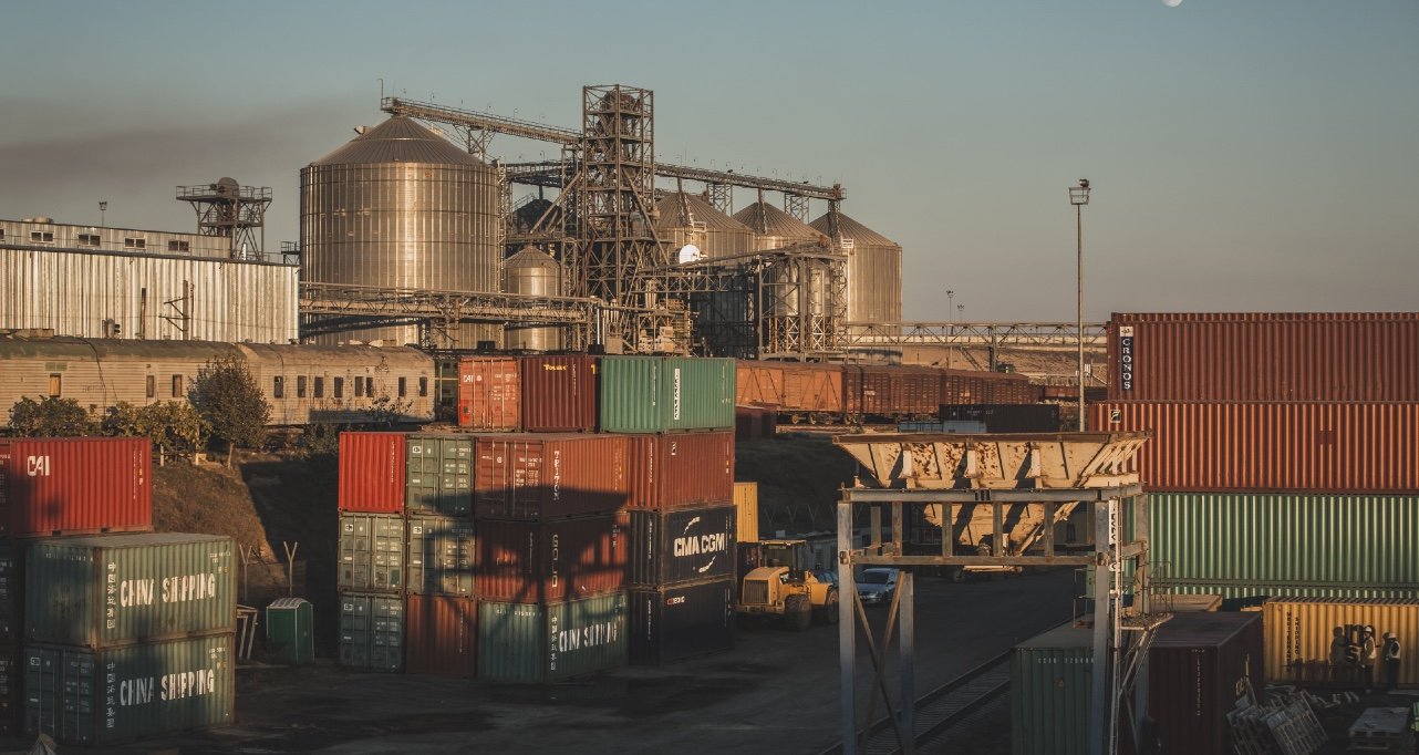 Контейнерная площадка порта Джурджулешть — грузовые контейнеры и зерновые элеваторы на закате. Фото: EBRD