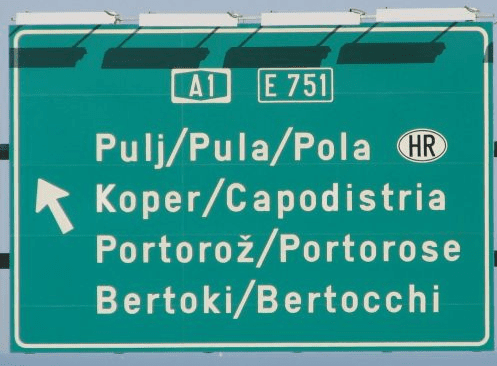 Двуязычный дорожный указатель на трассе A1/E751 с названиями населённых пунктов на словенском и итальянском: Pulj/Pula/Pola, Koper/Capodistria, Portorož/Portorose, Bertoki/Bertocchi
