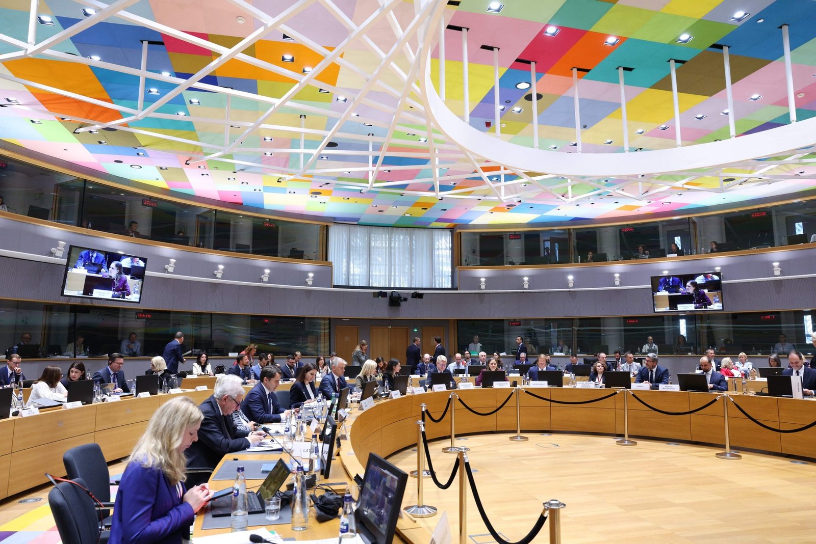 Зал заседаний Совета ЕС с характерным разноцветным потолком, делегаты сидят за круглым столом