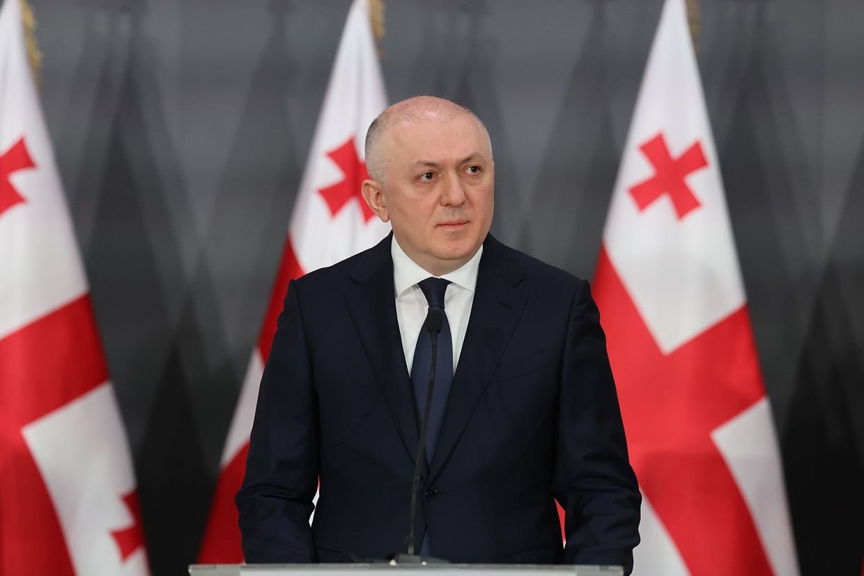 Official in suit with Georgian flags in background
