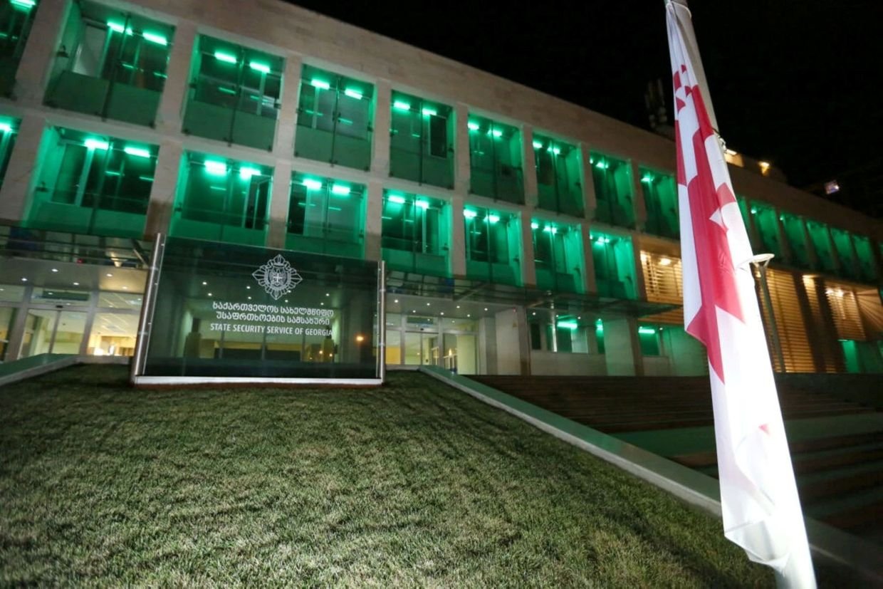 Здание Службы государственной безопасности Грузии ночью с грузинским флагом