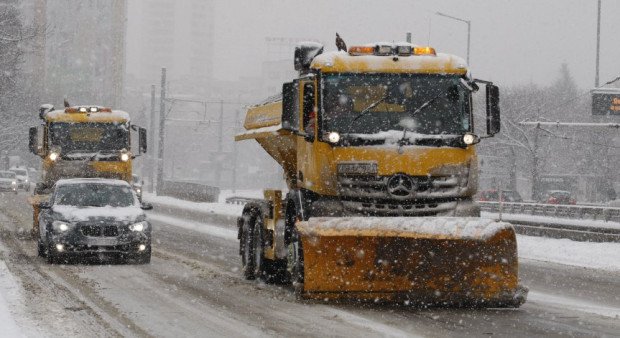 Yellow snowplows on highway during active snowfall