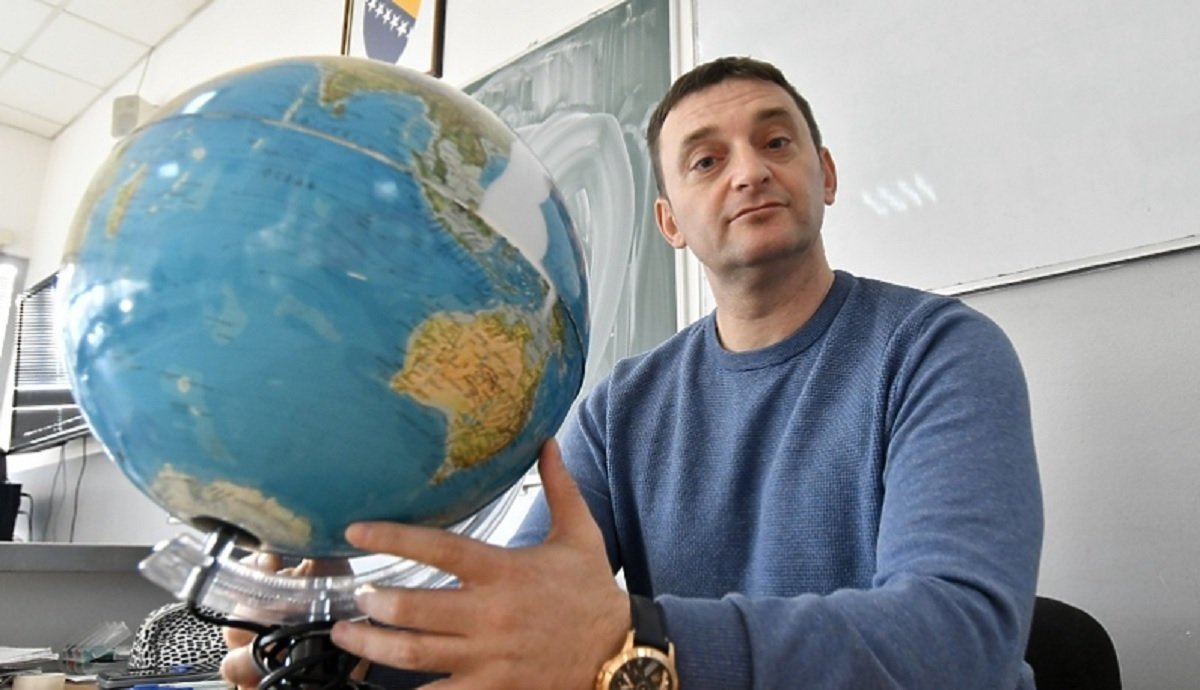Seismologist/professor holding globe in office setting - expert commentary source