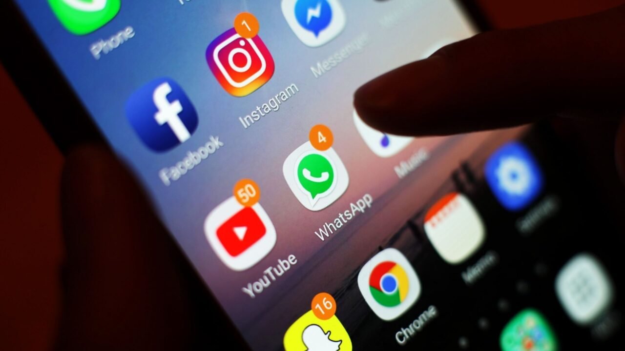Smartphone screen with social media apps (Facebook, Instagram, WhatsApp, YouTube) - channels for disinformation spread