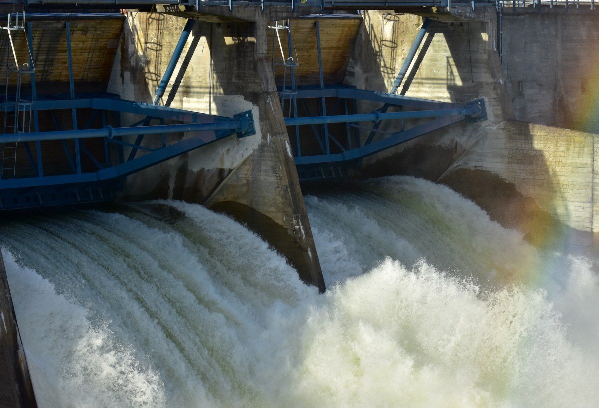 Dam floodgates with water rushing through, illustrating infrastructure vulnerability to cyberattacks