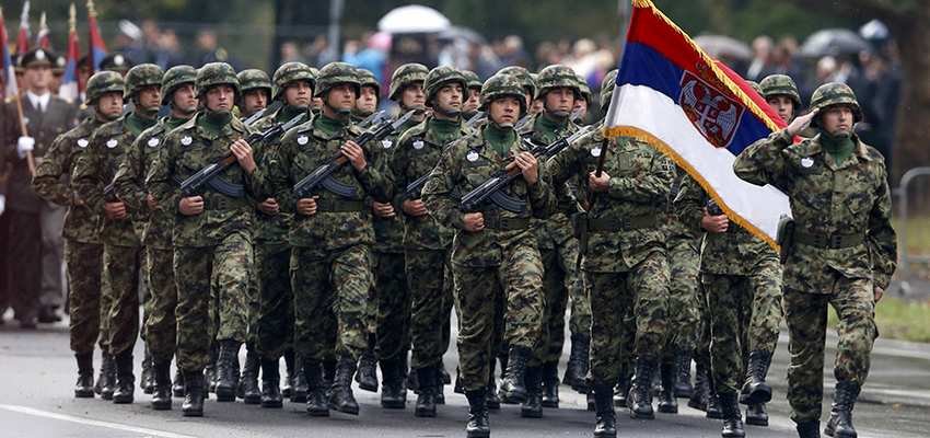 Военнослужащие Армии Сербии маршируют в строю с национальным флагом