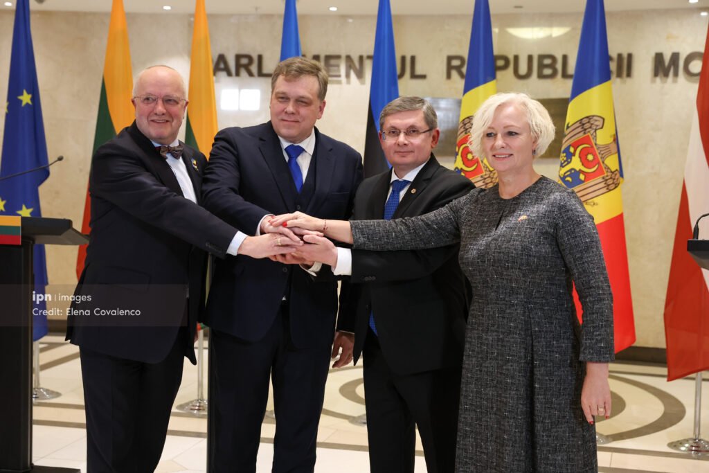 Four parliamentary speakers with joined hands in front of Moldovan Parliament sign, symbolizing solidarity